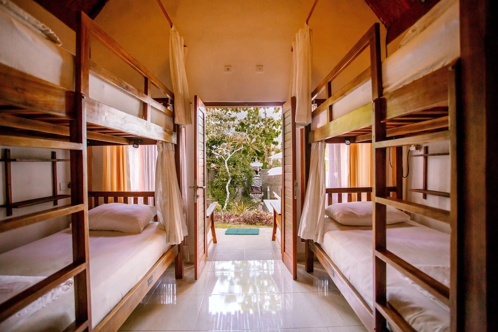 Cama en dormitorio compartido con balcón y con vista al jardín Nuansa Penida Hostel