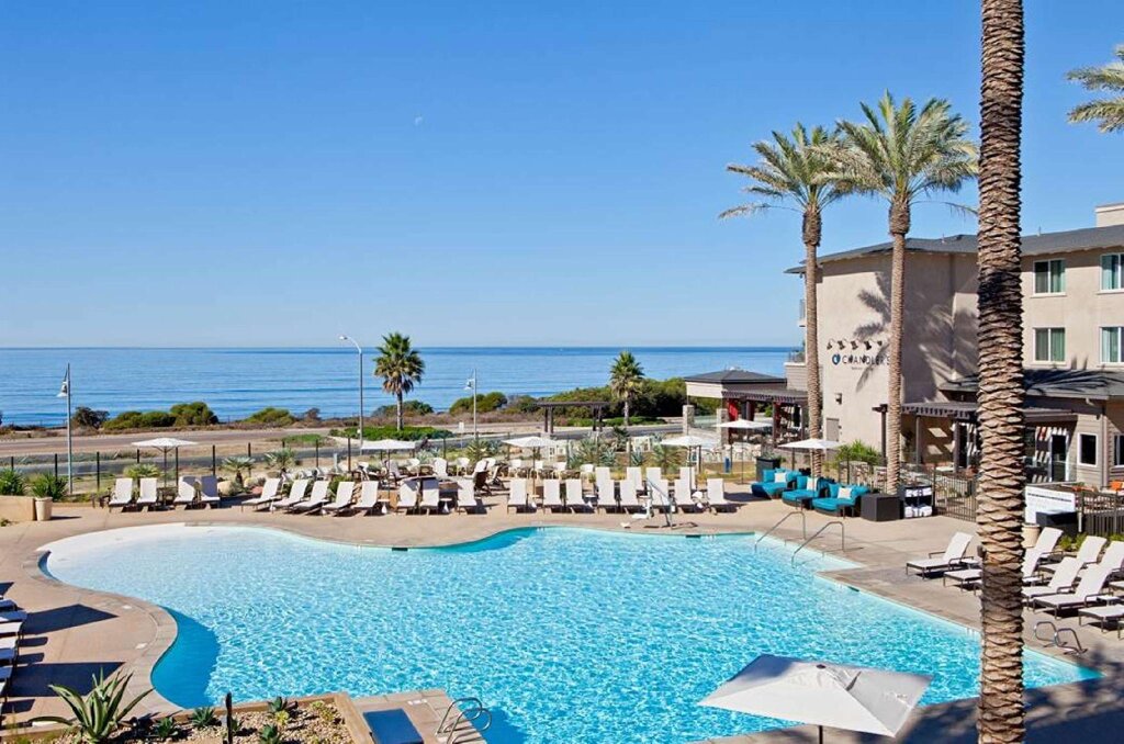 Cama en dormitorio compartido con vista a la piscina Cape Rey Carlsbad Beach, a Hilton Resort & Spa